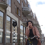 853432 Afbeelding van een fietsende vrouw in de Kaatsstraat te Utrecht, bellend met een mobiele telefoon.